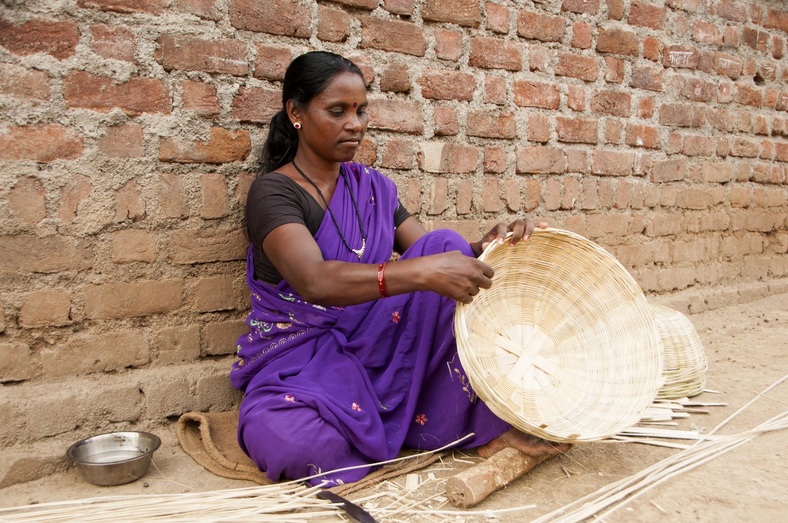Rural Indian woman weaving a bamboo basket by hand