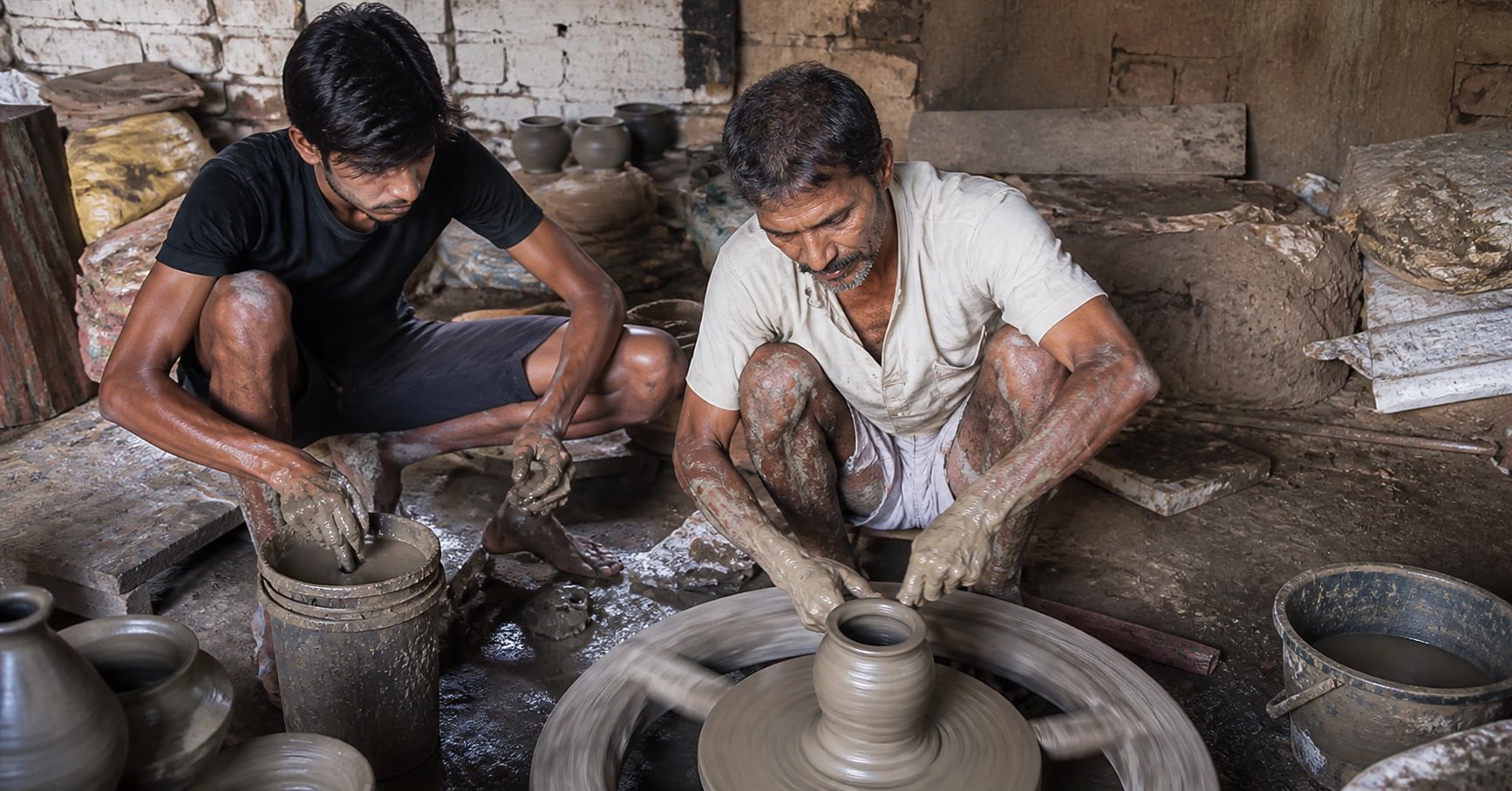 Master potter training a young apprentice at the wheel